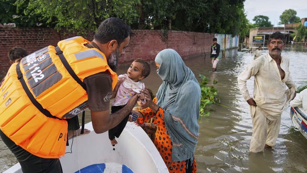 Rescue 1122 official saving a child during rescue operation for 2025 flood victims
